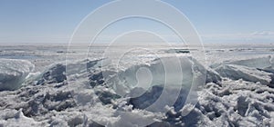 Transparent blue ice hummocks on lake Baikal shore. Siberia winter landscape view. Snow-covered ice of the lake. Big