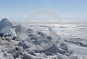 Transparent blue ice hummocks on lake Baikal shore. Siberia winter landscape view. Snow-covered ice of the lake. Big