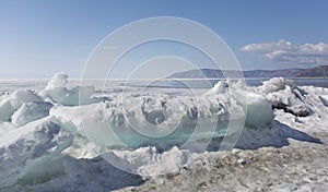 Transparent blue ice hummocks on lake Baikal shore. Siberia winter landscape view. Snow-covered ice of the lake. Big