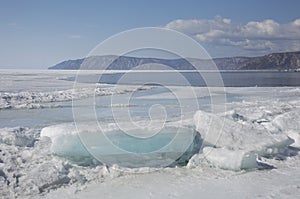 Transparent blue ice hummocks on lake Baikal shore. Siberia winter landscape view. Snow-covered ice of the lake. Big