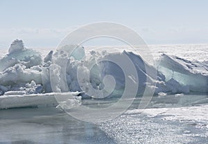 Transparent blue ice hummocks on lake Baikal shore. Siberia winter landscape view. Snow-covered ice of the lake. Big