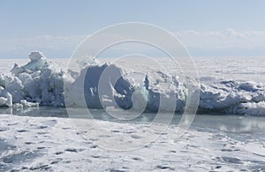 Transparent blue ice hummocks on lake Baikal shore. Siberia winter landscape view. Snow-covered ice of the lake. Big