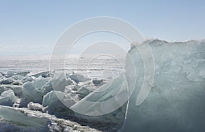 Transparent blue ice hummocks on lake Baikal shore. Siberia winter landscape view. Snow-covered ice of the lake. Big