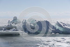 Transparent blue ice hummocks on lake Baikal shore. Siberia winter landscape view. Snow-covered ice of the lake. Big