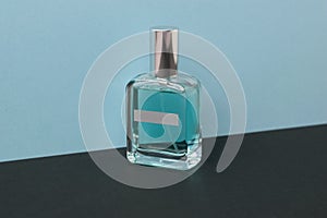 Transparent bottle with blue perfume on a black and blue background