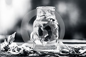 A transparent bottle contains rose water with rose petals in it photo