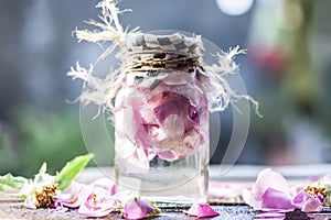 Rose water with rose petals on rough surface. photo