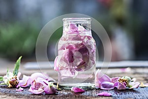 A transparent bottle contains rose water with rose petals in it photo