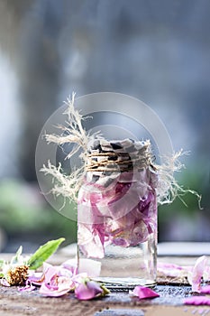 A transparent bottle contains rose water with rose petals in it photo