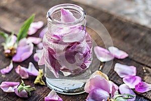 A transparent bottle contains rose water with rose petals in it photo