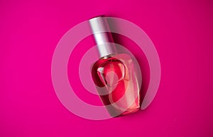 Transparent bottle of female perfume on a colored pink background. Top view. Womenaccessories photo