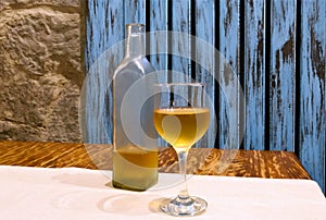 Transparent bottle and glass of white on table. Wooden background in rustic style