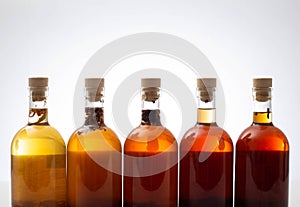 Transparent bottles with brown alcoholic drink on a white background. The concept of homemade herbal tinctures from