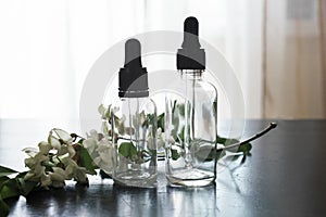 Transparent bottles of cosmetics with fresh flowers are on the table. Cosmetic oil