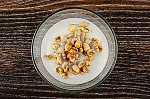 Transparent bowl with yogurt, puffed wheat on wooden table. Top view