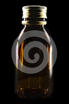 Transparent brown jar with a metal lid appears on a black background