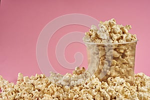 Transparent bucket full of sweet popcorn on pink background