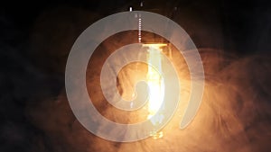 Transparent Bulb Hanging on Wire and Flickering on Black Background with Smoke