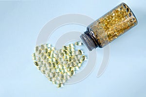 Transparent capsules with vitamin D or Omega-3 in the form of a heart and and a can of vitamins are on a blue background.