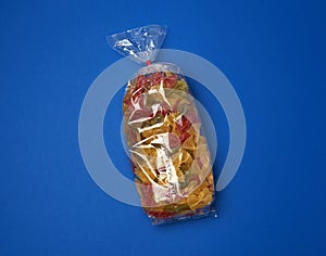 Transparent cellophane bag with raw colorful pasta in the form of bows