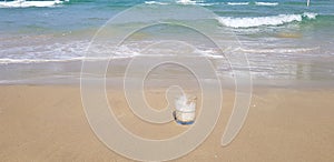 transparent coffee glass stands in wet sand