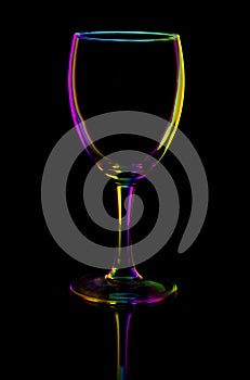 Transparent colored empty wine glass on black