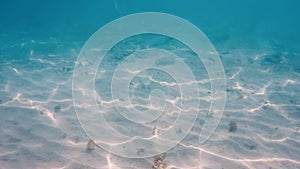 Transparent crystal blue ocean water with white sand bottom. Underwater view of searipple with light making caustic on