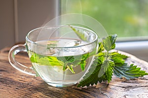 Transparent cup with nettle tea. fresh nettle on a wooden board.