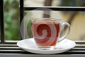TRANSPARENT CUP WITH RED LIQUOR TEA BESIDE THE WINDOW photo