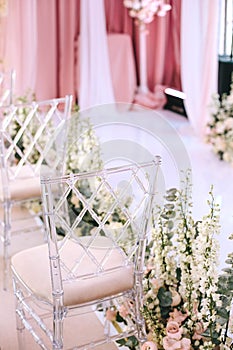 Transparent design chairs at the wedding ceremony decorated with white flowers