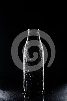 Transparent empty glass bottle with condensate on black