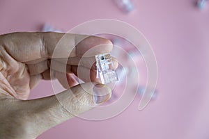 Transparent ethernet internet RJ-45 connectors, tehnology background on pink with hand