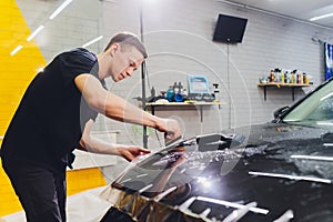 Transparent film, car paint protection, wrapping specialis. Car detailing. Selective focus.