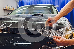 Transparent film, car paint protection, wrapping specialis. Car detailing. Selective focus.