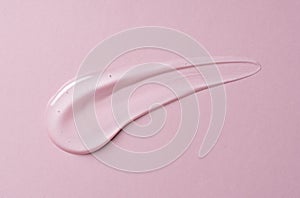 Transparent gel drop on pink background. Liquid gel cosmetic stain texture. Beauty serum drop