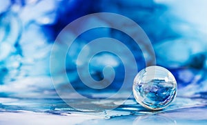 A transparent glass ball on an abstract blue background. The technique of alcoholic ink. Copy space.