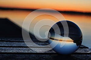 A transparent glass ball flips the pier and the sunset on the lake