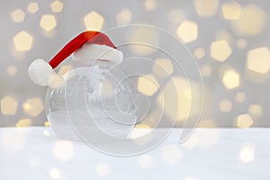 transparent glass ball on snow with christmas hat. snow and bokeh flare on Santa Claus Hat.