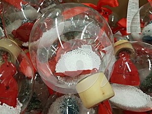Transparent glass balls with artificial snow and red figures.