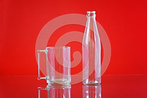 Transparent glass bottle and cap on a bright red background. Container for liquids. Free space for an inscription