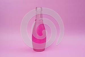 Transparent glass bottle with colorful hot pink liquid, unusual background