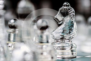 transparent glass chess on dark background, selective focus on horse piece, close-up