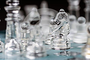 transparent glass chess on dark background, selective focus on horse piece, close-up