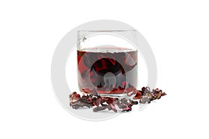 Transparent glass cup with Hibiscus tea with dry tea leaves on a white background.