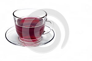 Transparent glass cup with Hibiscus tea on a saucer isolated