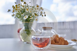 Transparent glass Cup of tea in nature. The concept of breakfast in the backyard of the house. Early morning, tea and