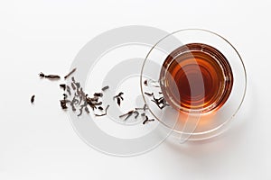 Transparent glass cup with tea on the saucer with dry tea leaves