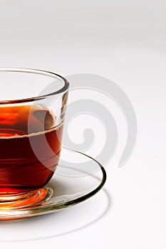 Transparent glass cup tea on a saucer on a white background