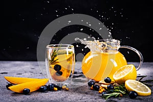 Transparent glass cup and teapot with fruit tea, on a black and gray background