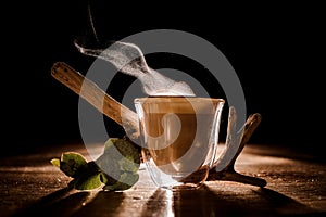 Transparent glass of a delicious hot coffee on the dark background